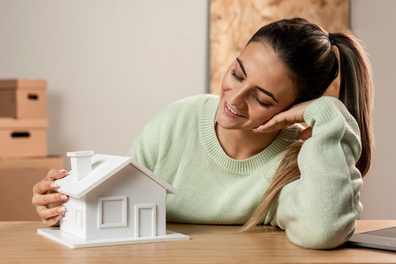 A laughing woman has a model and a house in her hand.
