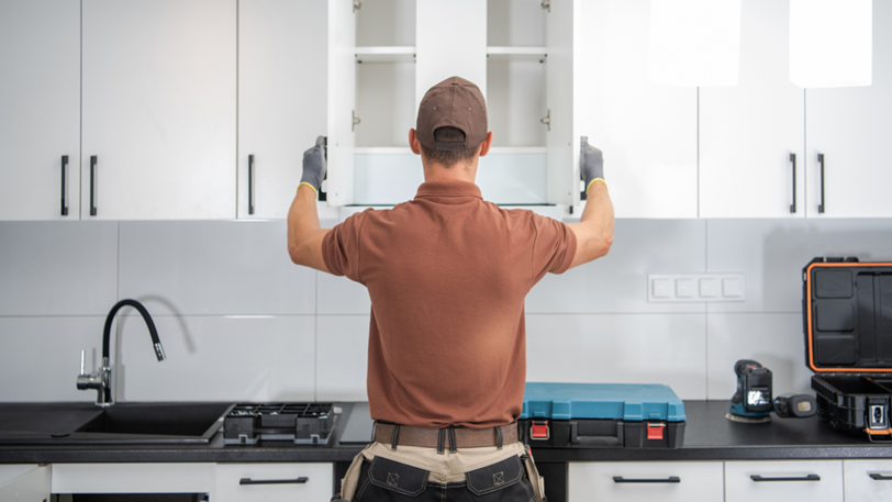A general contractor examines newly installed cabinets in a remodeled kitchen.