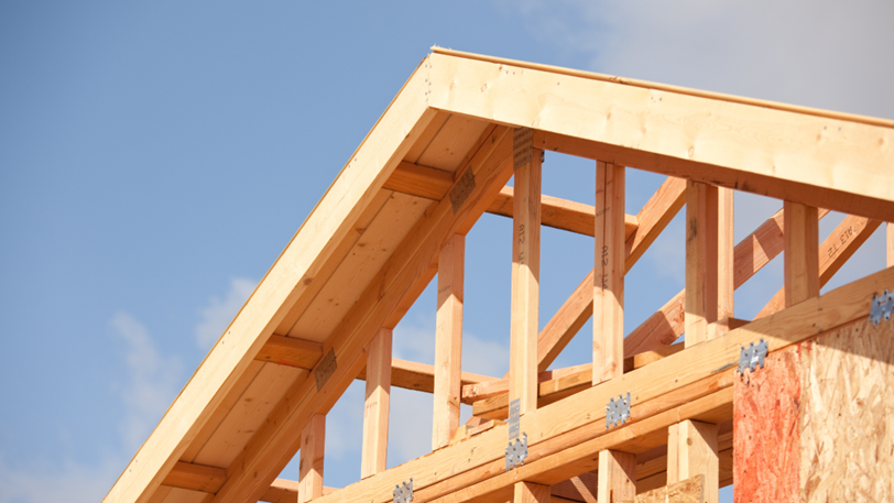 The roof of a house that is in the process of being built, under a blue sky.