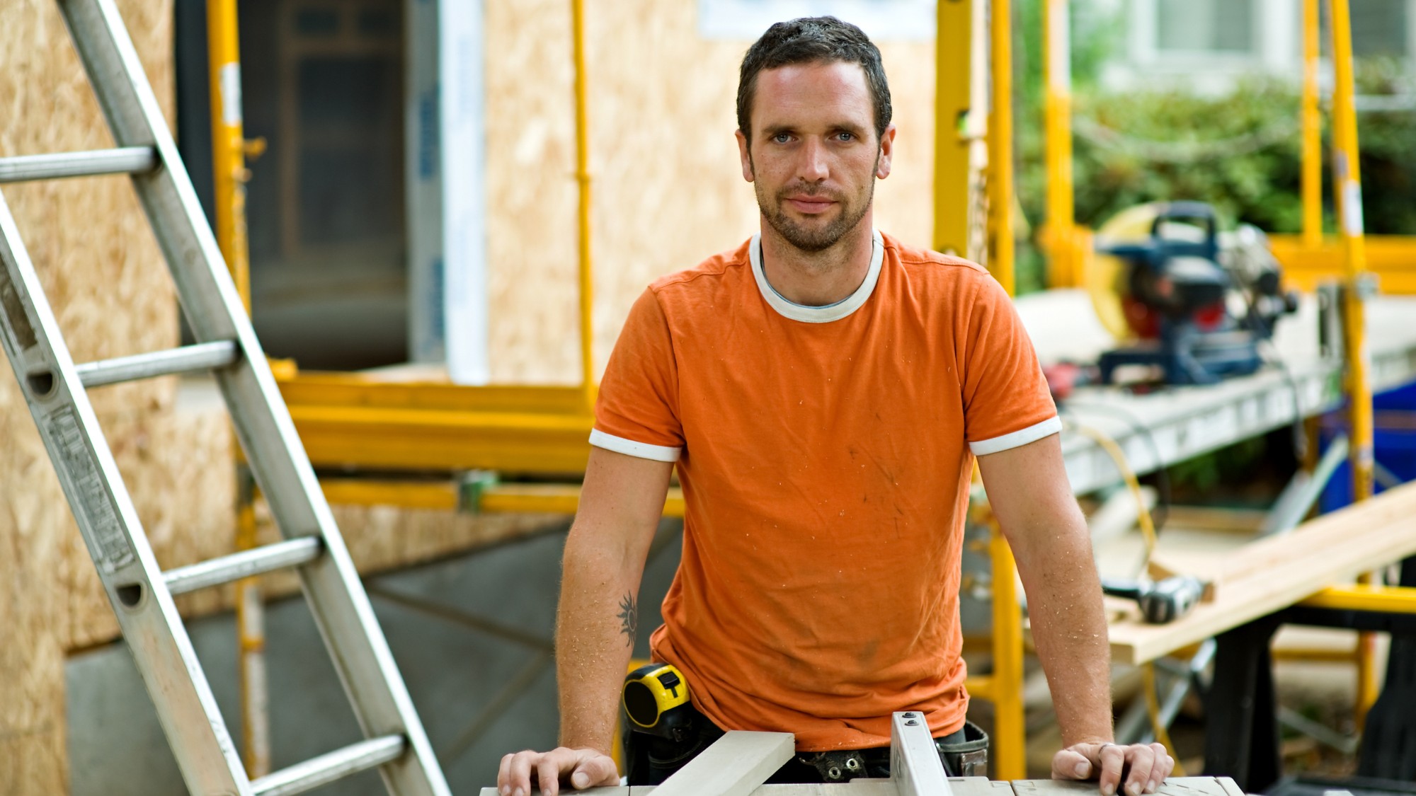 A general contractor on a job site wearing an orange shirt.